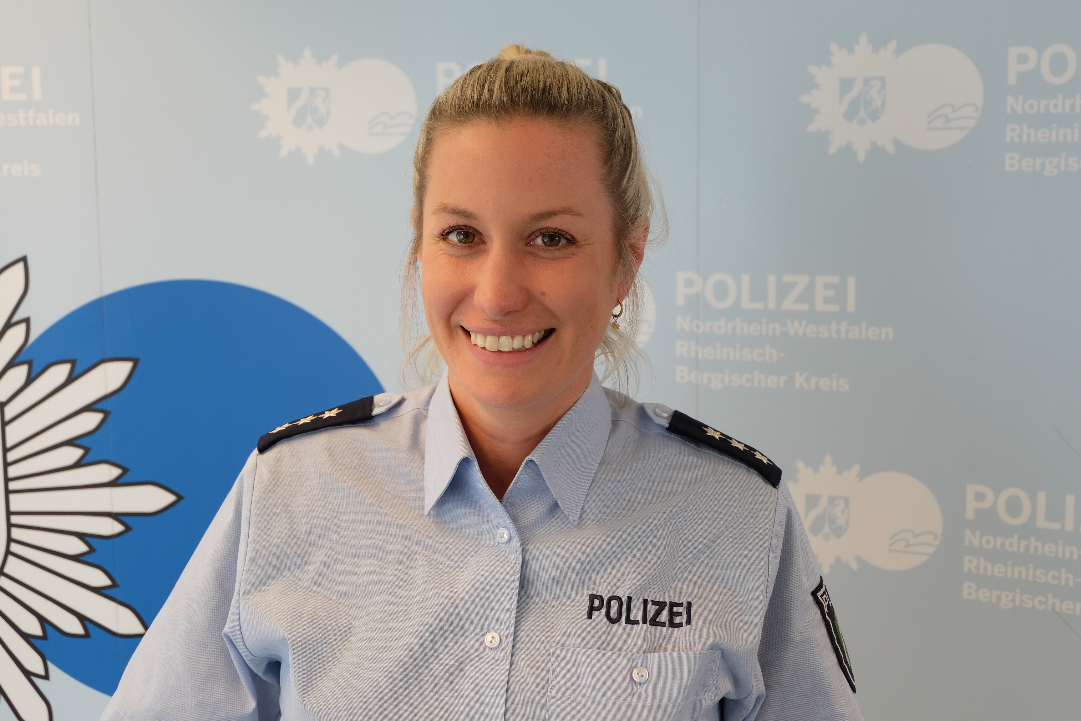 Porträt der Polizeihauptkommissarin Hanna Leis vor der Presseleinwand 